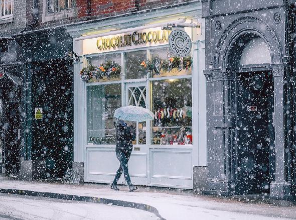 Marcher devant les cafés et les magasins à Noël alors qu'il neige